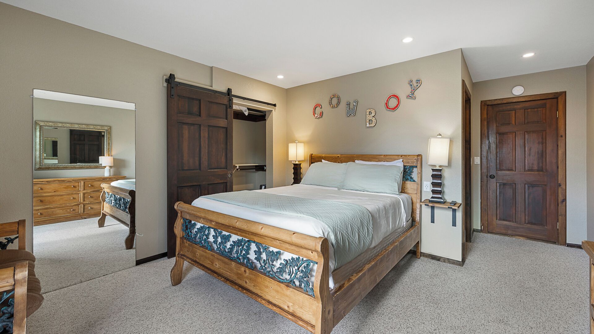 A bedroom with a large bed, a dresser, a mirror, and a wardrobe.