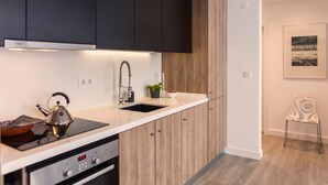 Een moderne keuken met een ingebouwde kookplaat, gootsteen en donkere kastjes.