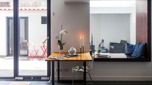 Een modern interieur met een houten tafel, een stoel, een vaas met bloemen, een kaars en een boekenplank.