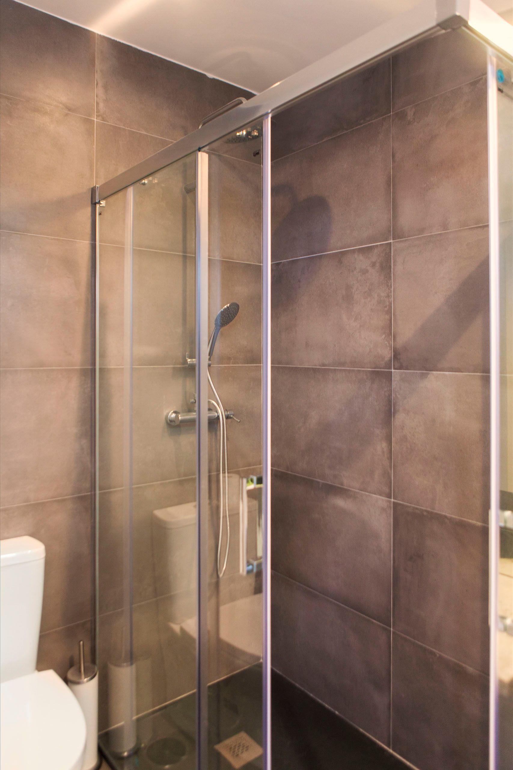 A modern bathroom with a glass-enclosed shower, a toilet, and a sink.