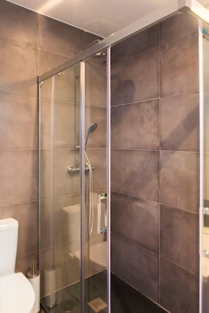 A modern bathroom with a glass-enclosed shower, a toilet, and a sink.