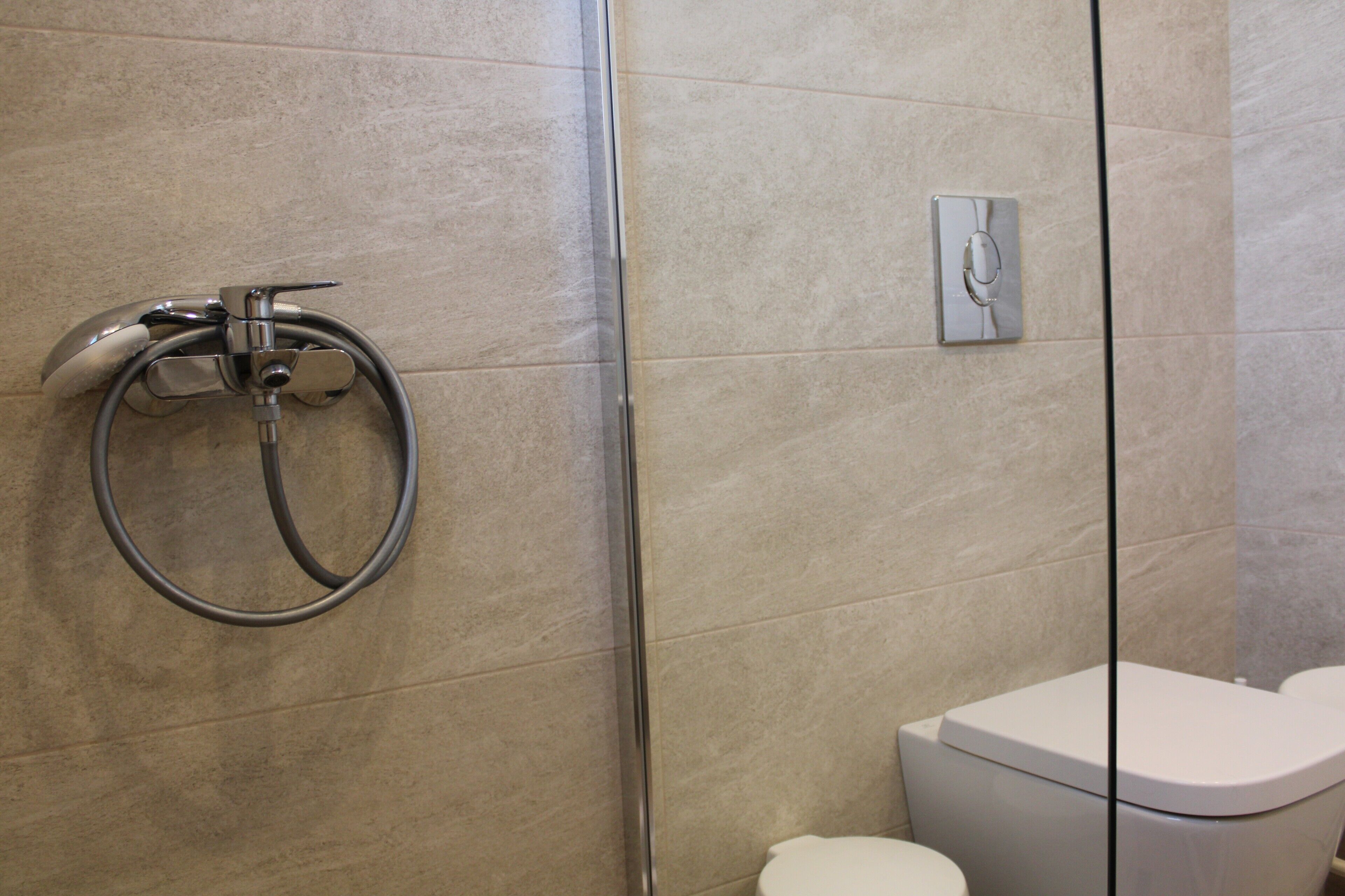 Un baño moderno con cabina de ducha de vidrio, un inodoro y un panel de control en la pared.