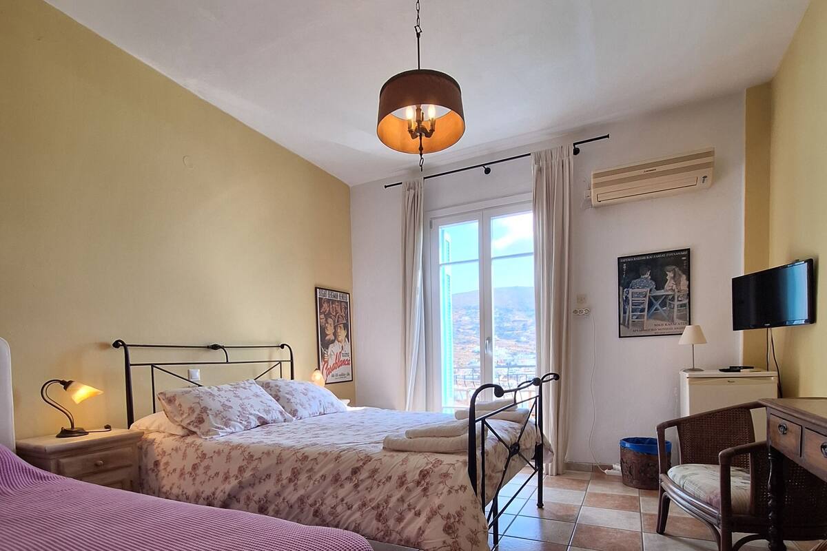 Un dormitorio con dos camas, un escritorio, una silla, un televisor y una ventana con cortinas.