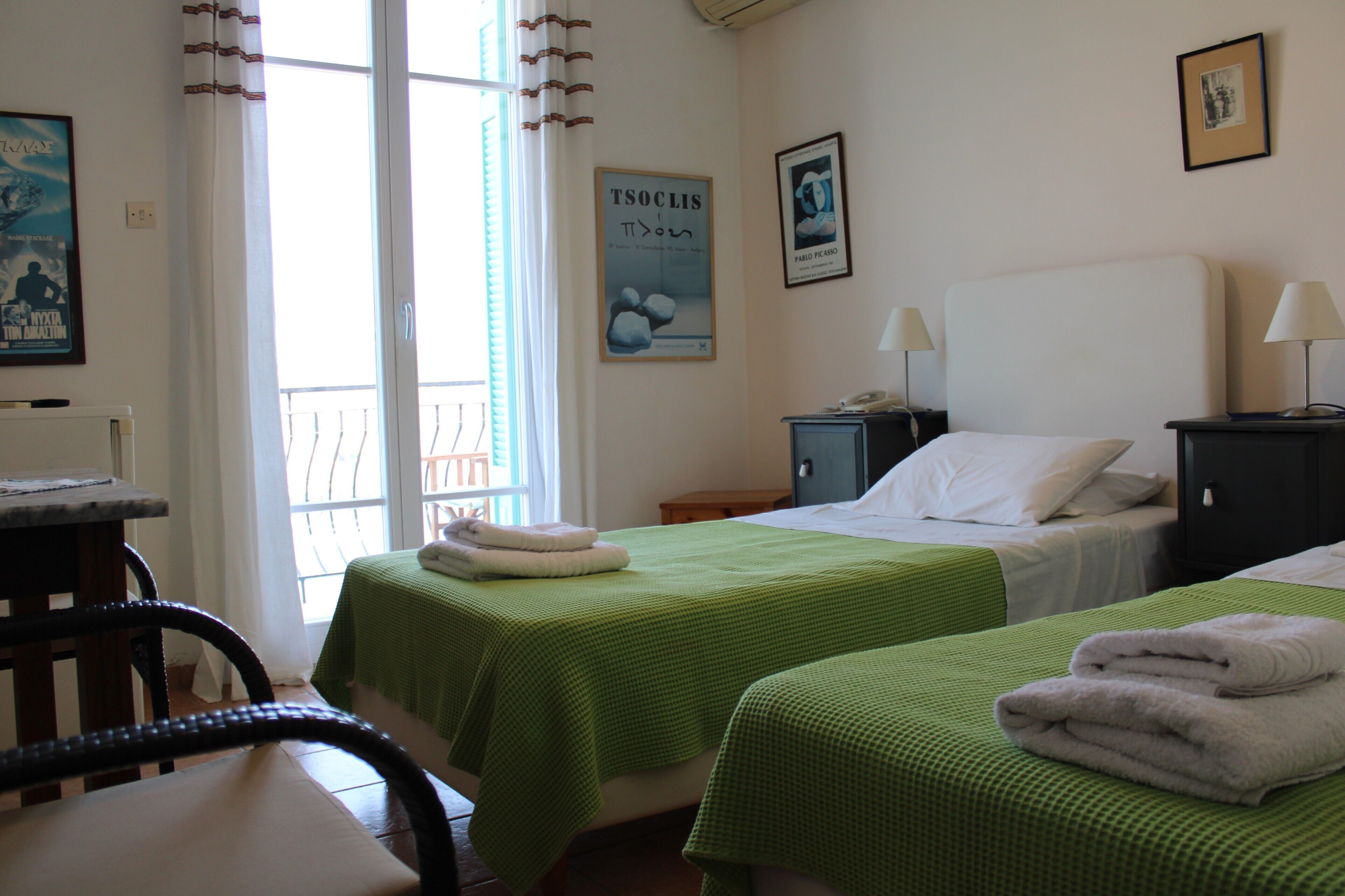 A hotel room with two beds, a desk, and a chair. There are towels on the beds and a poster on the wall.