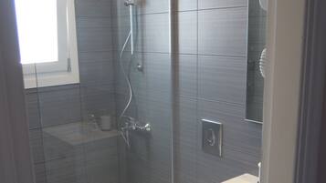 Une salle de bain moderne avec une douche à parois de verre, des toilettes et un lavabo.