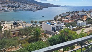 A coastal town with white buildings, a clear blue sea, and a mountainous backdrop. - Blue Dolphin (Andros)