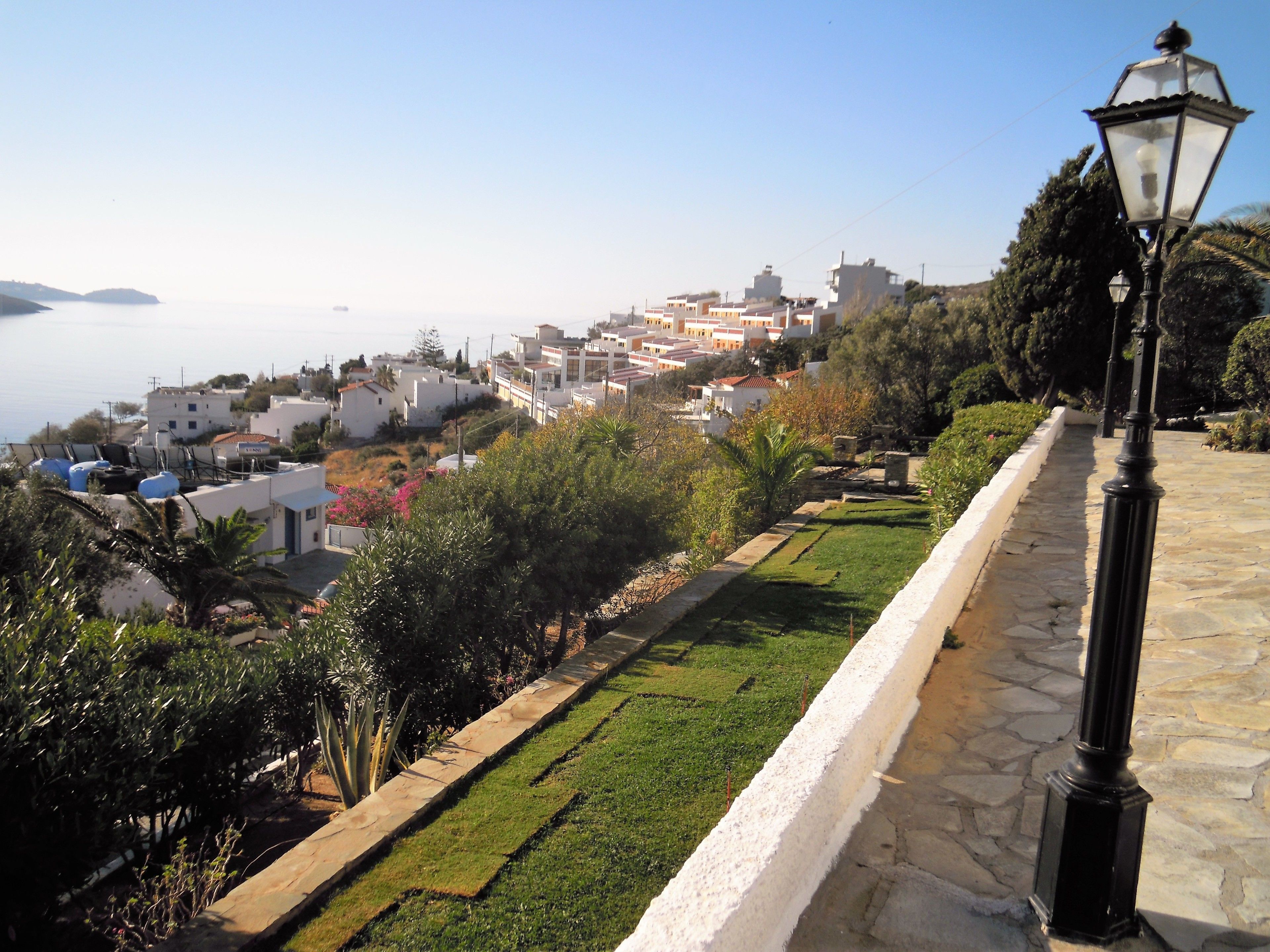 Un pueblo costero con edificios blancos, un camino de piedra y un farol.