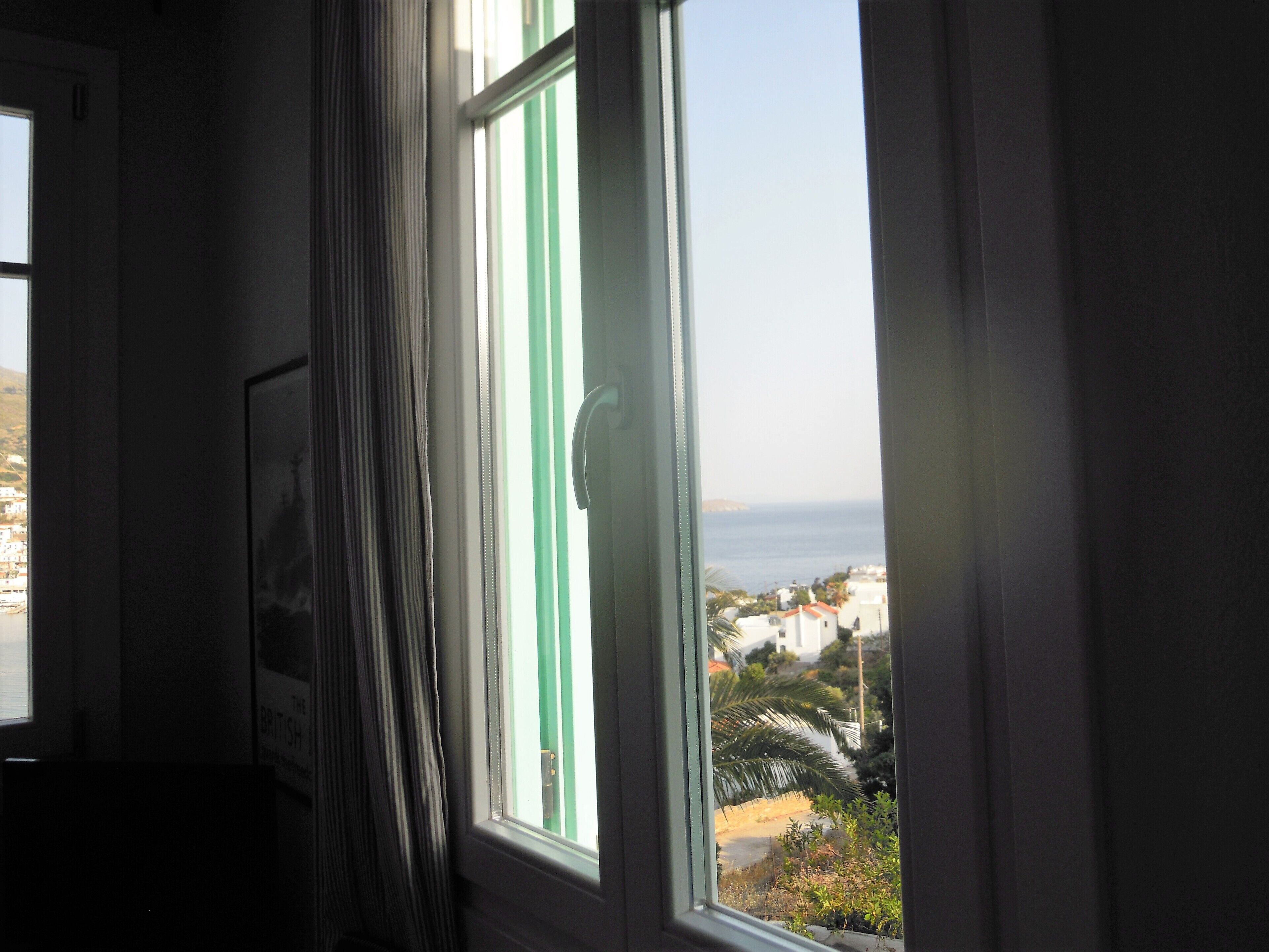 A room with a window overlooking a coastal view, a door, and a framed picture on the wall.