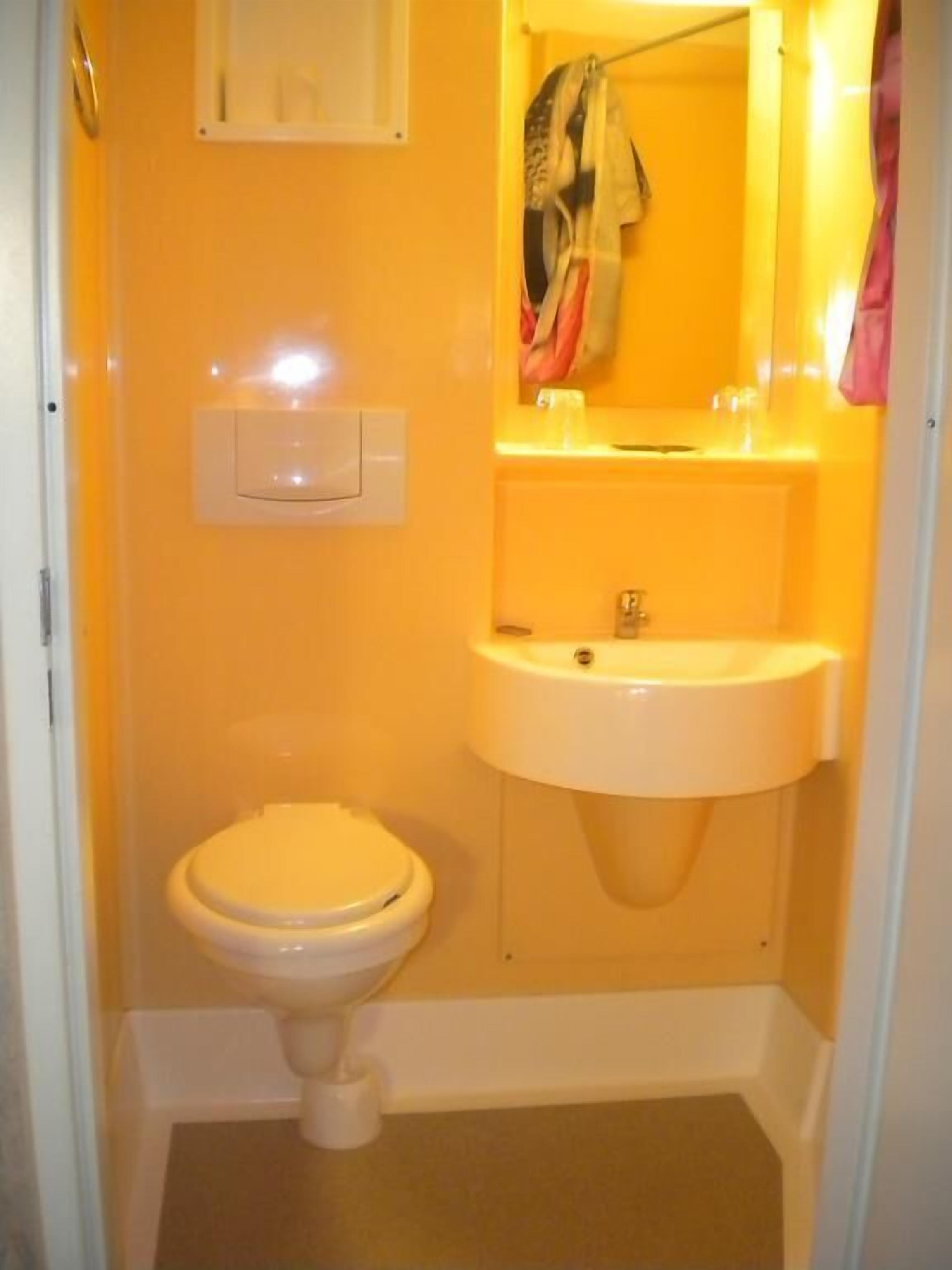 A small bathroom with a toilet, sink, and mirror.