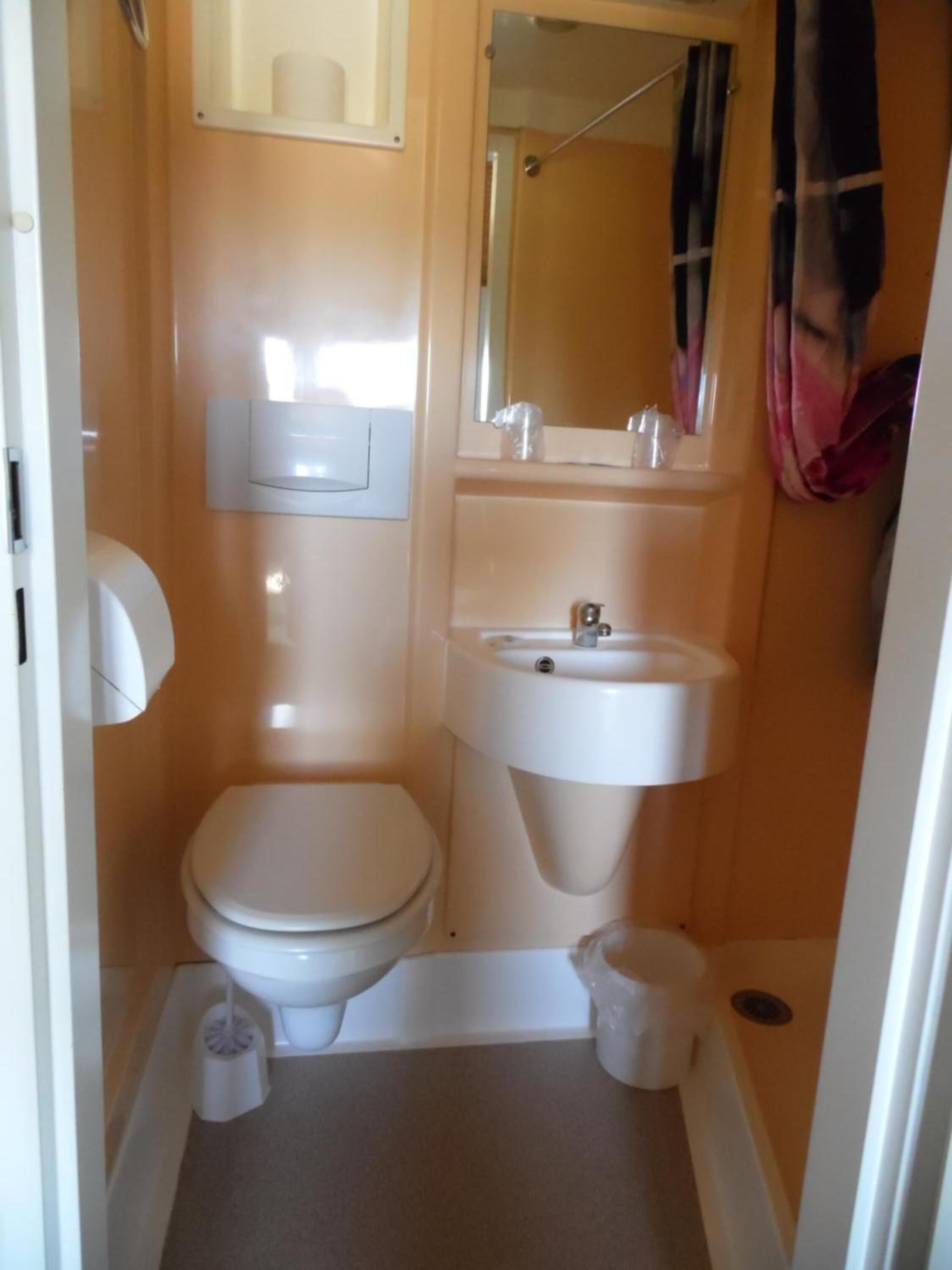 Een kleine badkamer met toilet, wastafel en spiegel.