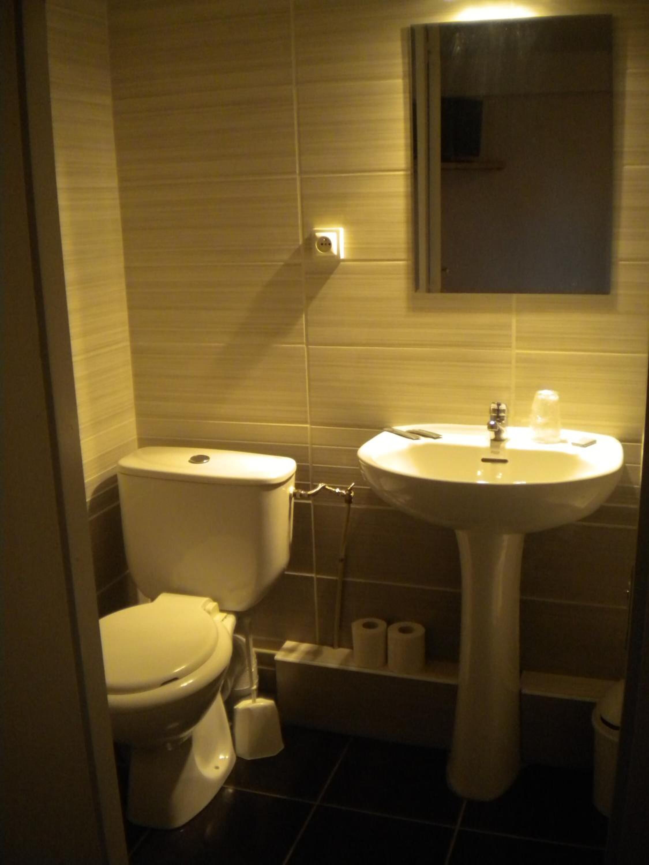A small bathroom with a toilet, sink, and a mirror above the sink.