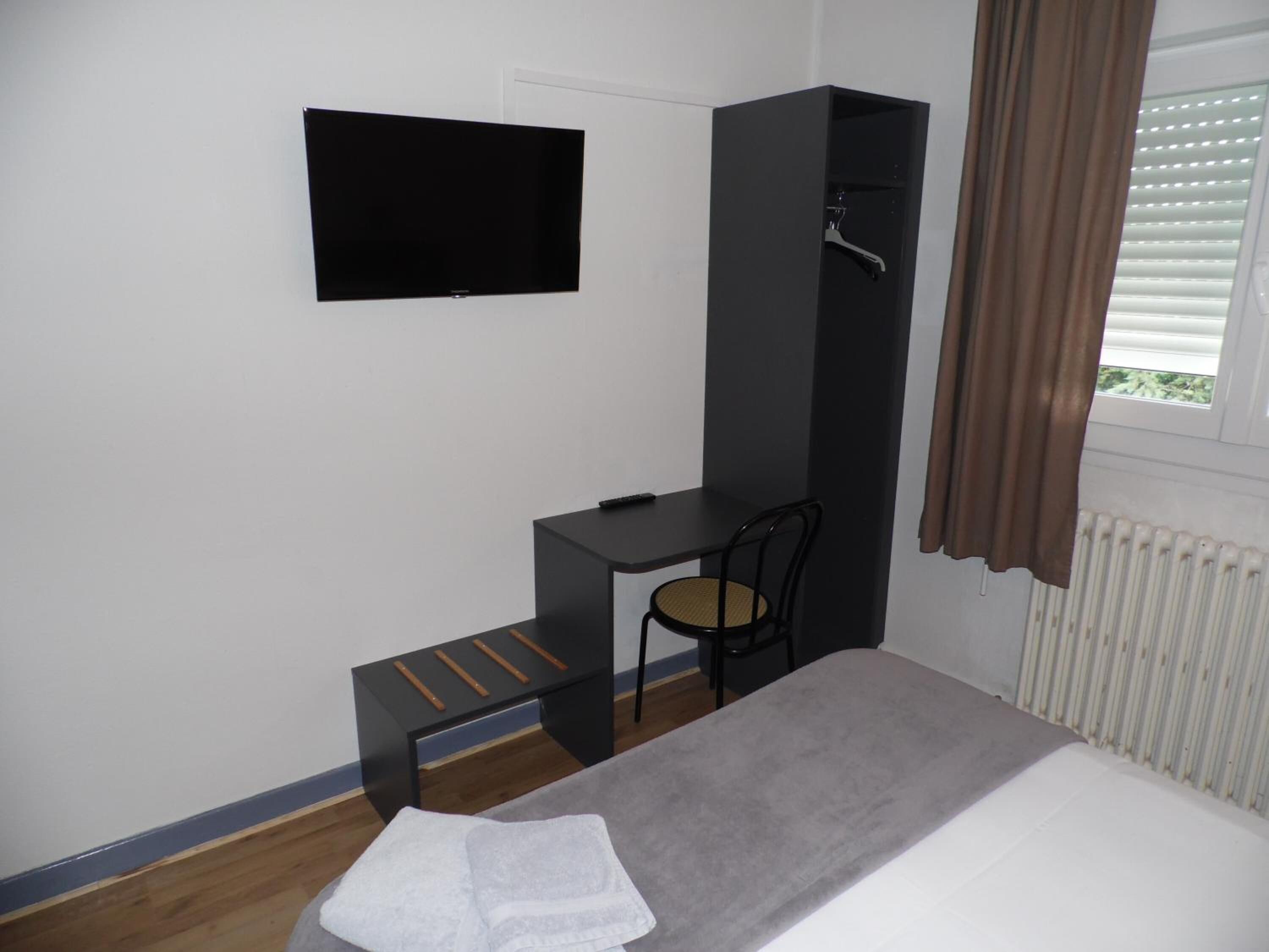 Une chambre à coucher avec un lit, un bureau, une chaise, un téléviseur et un radiateur.