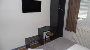Une chambre à coucher avec un lit, un bureau, une chaise, un téléviseur et un radiateur.