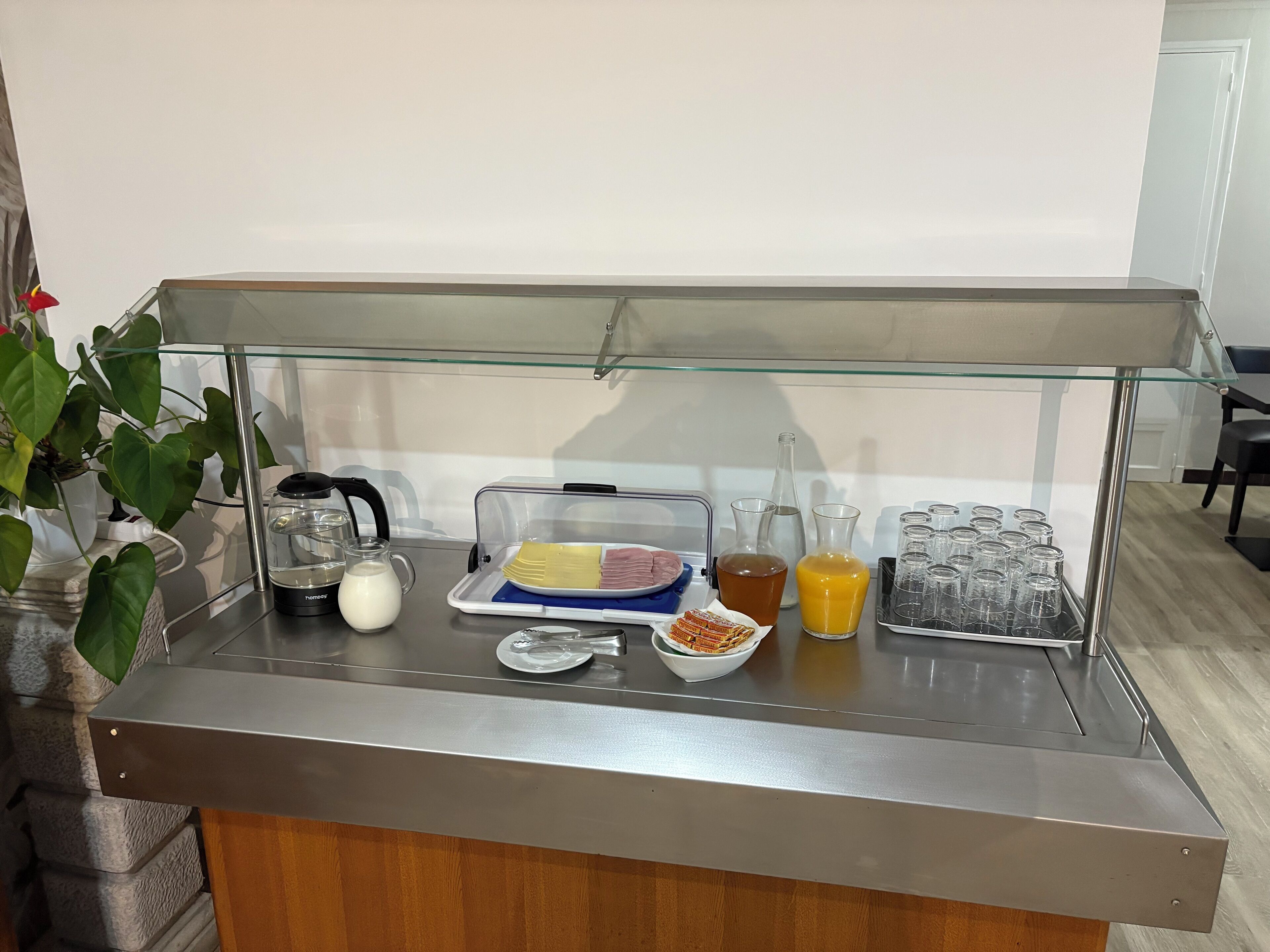 A breakfast buffet with a variety of food items and beverages, including a milk jug, a fruit tray, and several glass containers.