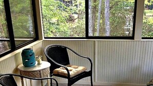 Ein Zimmer mit zwei Korbstühlen, einem kleinen runden Tisch mit einer Vase und einem gemusterten Teppich.