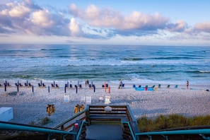A beach with a wooden walkway leading to the shore, beach chairs, and umbrellas.