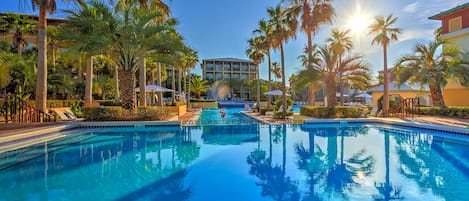 Relax by the pool surrounded by palm trees and lounge chairs.