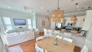 Una sala moderna con sofá, mesa de comedor y sillas. Cuenta con una zona de cocina con armarios y electrodomésticos.
