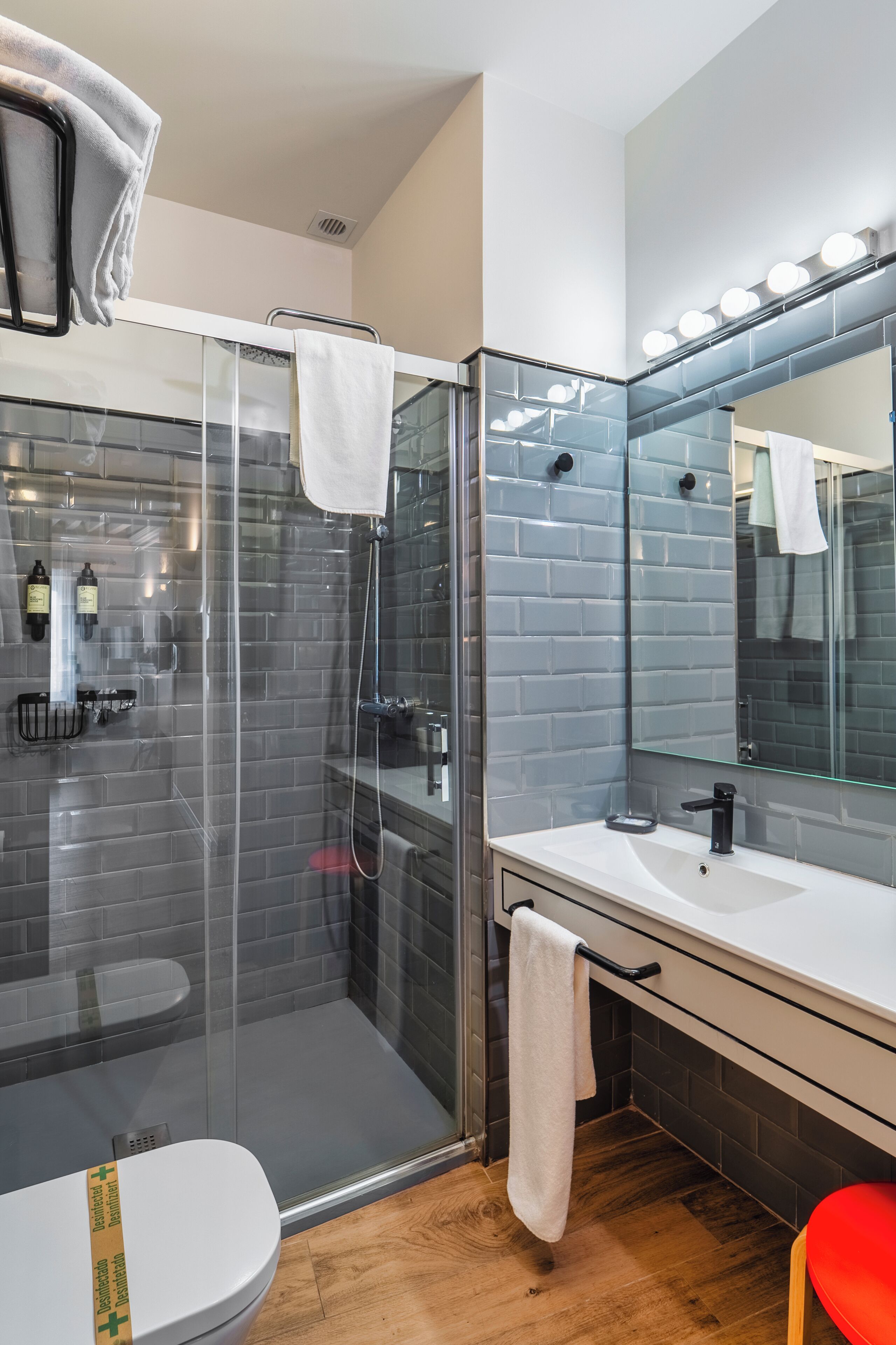 Ein modernes Badezimmer mit einer gläsernen Dusche, einem weißen Waschbecken und einem großen Spiegel mit Beleuchtung.