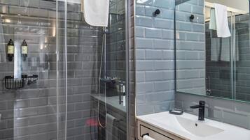 Ein modernes Badezimmer mit einer gläsernen Dusche, einem weißen Waschbecken und einem großen Spiegel mit Beleuchtung.