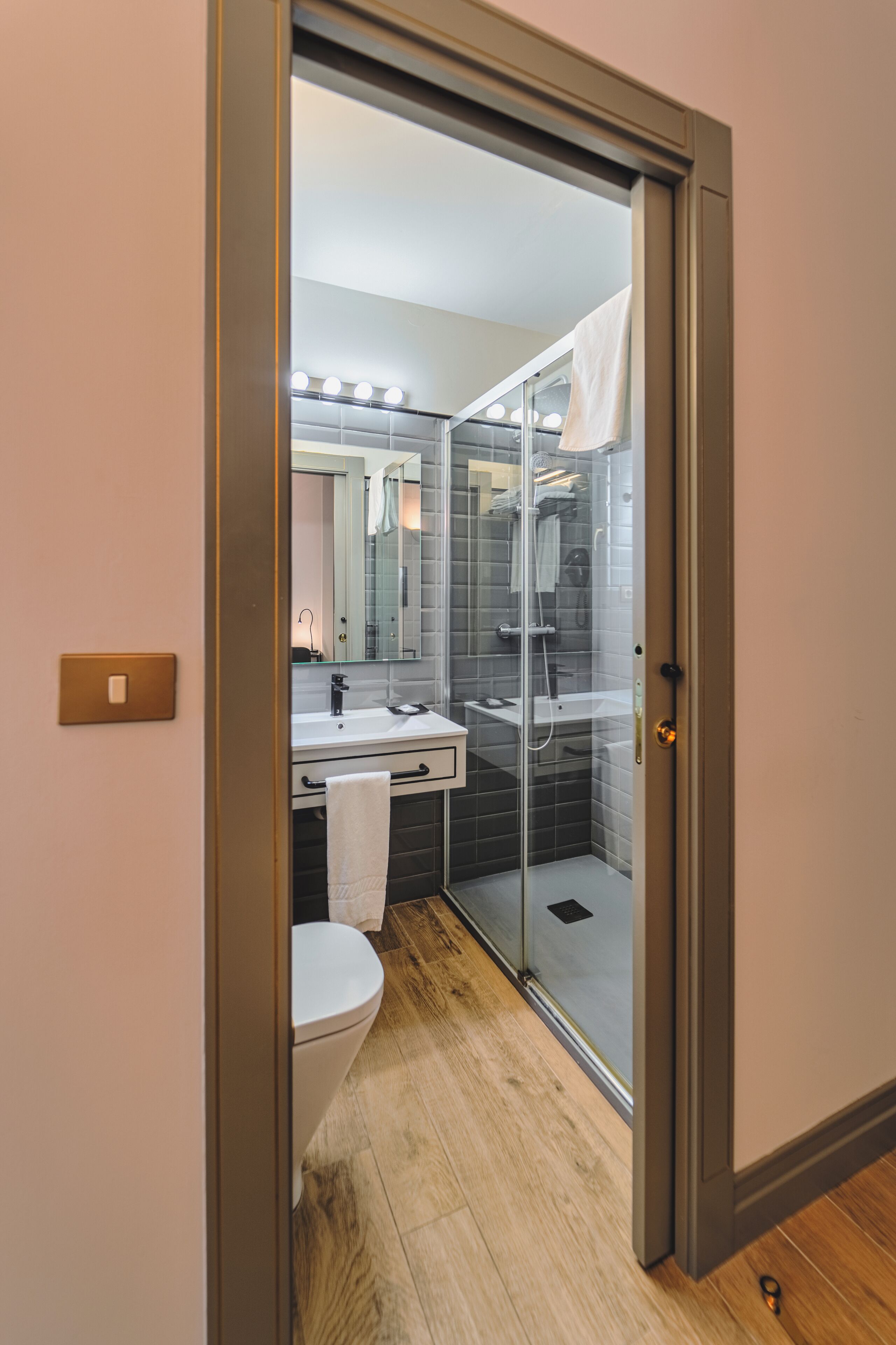 Un baño moderno con cabina de ducha de vidrio, un lavamanos blanco y un inodoro.