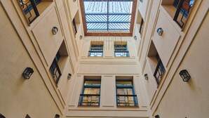 Un atrio de varios niveles con tragaluces, varios balcones y una entrada central con una puerta azul.