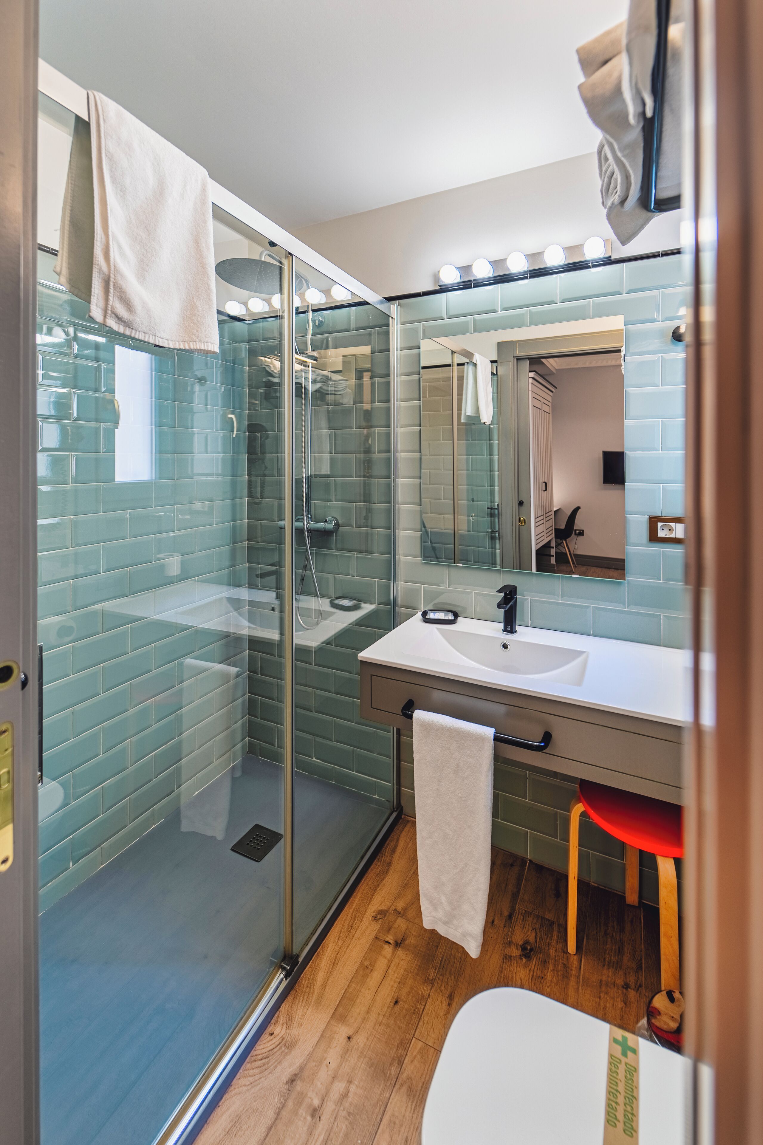 A modern bathroom with a glass shower enclosure, a white sink, and a large mirror.