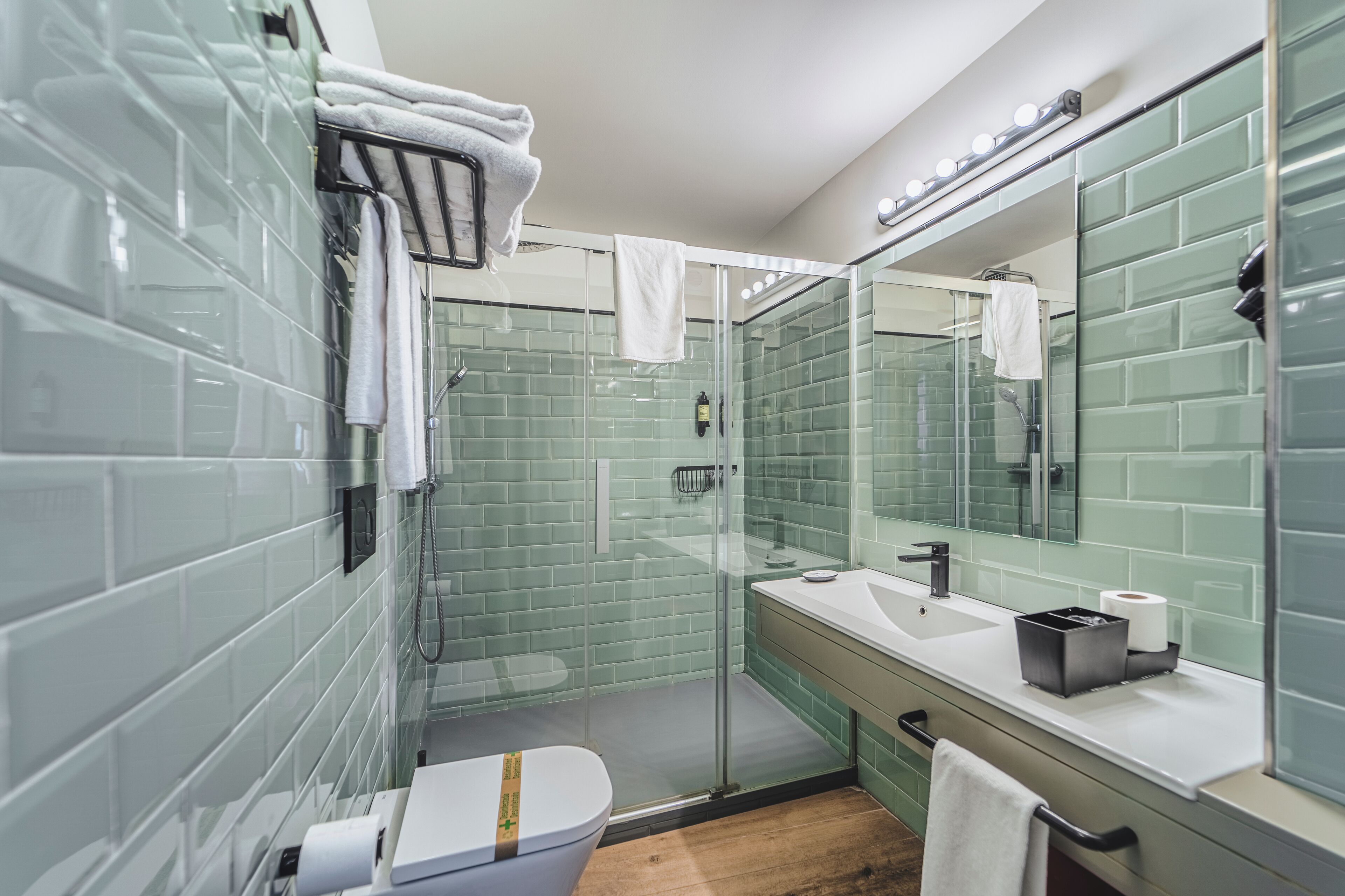 Un baño moderno con cabina de ducha de vidrio, inodoro blanco y lavamanos con espejo.