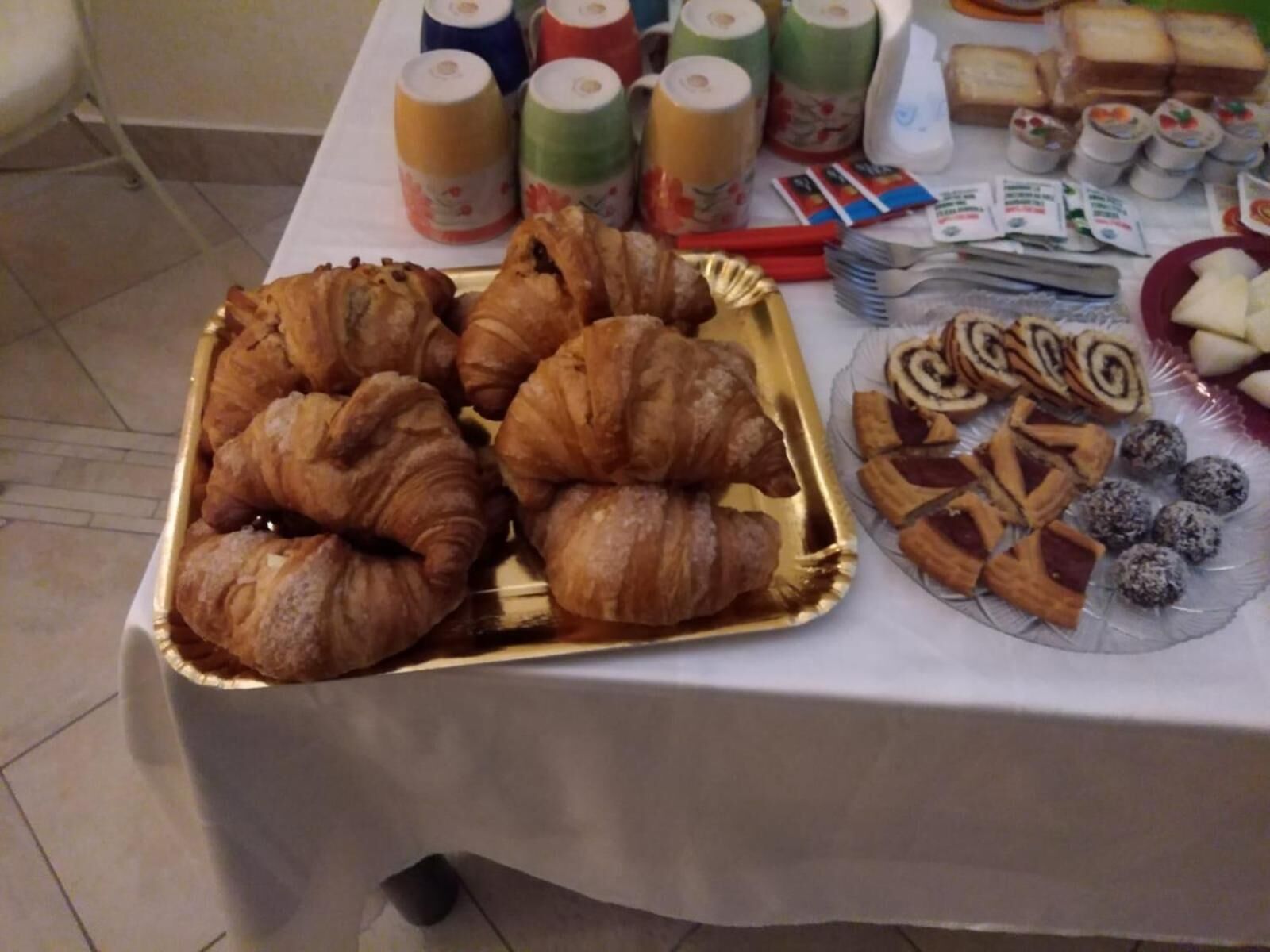 A buffet table with croissants, pastries, and rolls.