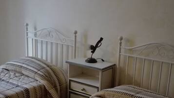 Quarto com duas camas, mesa de cabeceira com abajur e quadro na parede.