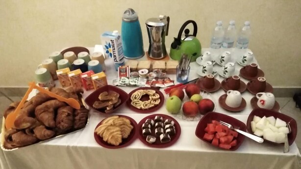 Una mesa con diversos alimentos y bebidas, como pasteles, frutas y una tetera.