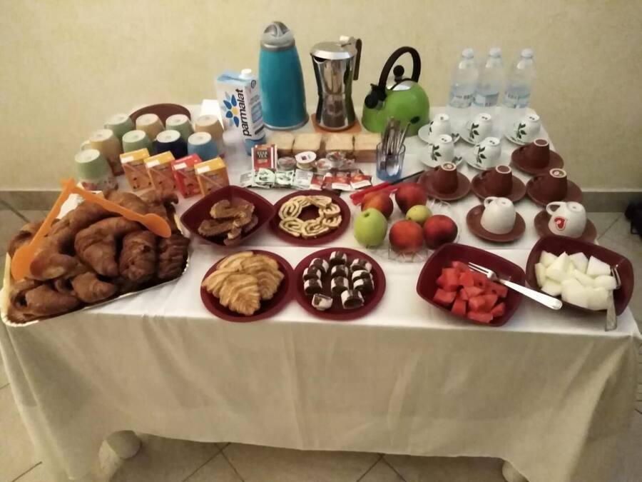 A table with various food items and beverages, including pastries, fruits, and a teapot.