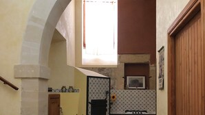 Una cocina con piso de baldosas, una ventana con cortina, estufa y pileta.