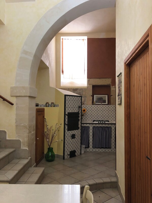 A kitchen with a tiled floor, a window with a curtain, a stove, and a sink. - B&B Candido Vacanze (Modica)