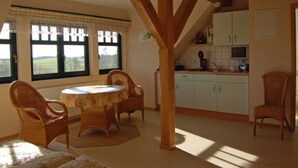 A dining area with a table and chairs, a kitchen with cabinets, and a window with a view of the outdoors.