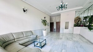 Un salon moderne avec un canapé d’angle gris, une table basse en verre et un lustre.