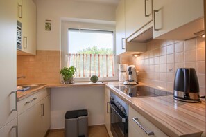 A compact kitchen with a window, a coffee maker, and a trash bin.