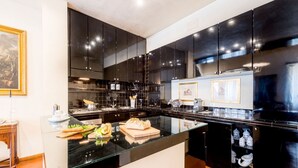 Una cocina moderna con armarios negros, una isla de vidrio y un salpicadero de azulejos.