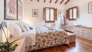 Un dormitorio con cama, vigas de madera, un escritorio y una ventana.