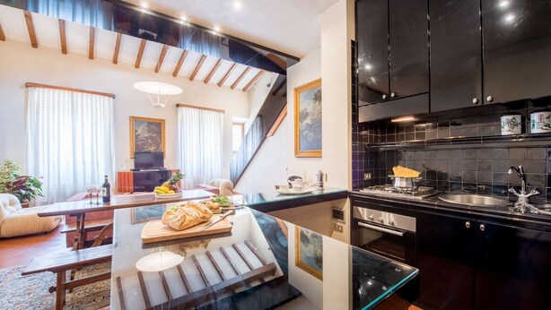 Una cocina moderna con armarios negros, una isla de vidrio y un área de comedor con sofá y mesa.