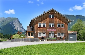 Ein Holzhaus mit einem Schild, auf dem 'Ferienwohnungen Schantl' steht, vor einer Bergkulisse.