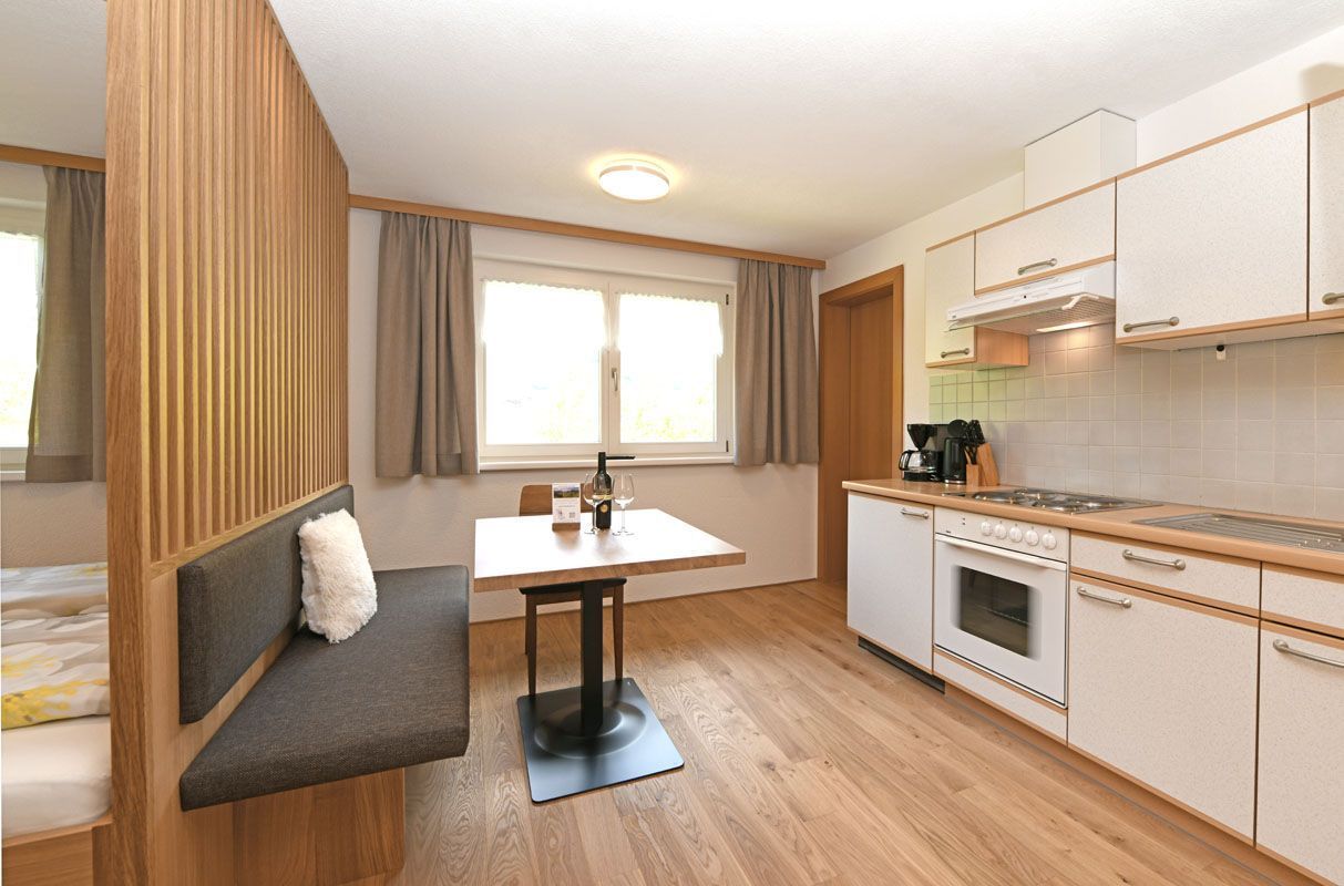A compact kitchen with a dining area, a built-in bench, and a window with curtains.