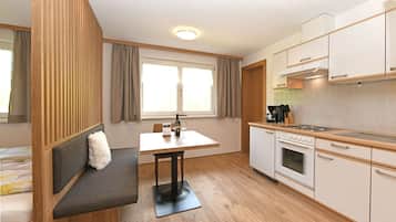 A compact kitchen with a dining area, a built-in bench, and a window with curtains.