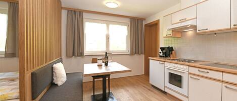 A compact kitchen with a dining area, a built-in bench, and a window with curtains.