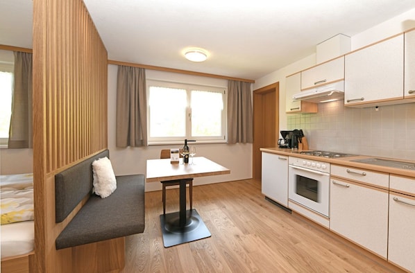 Una cocina compacta con zona de comedor, un banco empotrado y una ventana con cortinas.