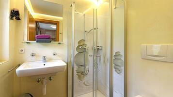 Une salle de bain avec une douche à parois de verre, un lavabo, un miroir et un porte-serviettes.