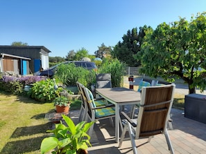 A patio with a table and chairs, surrounded by potted plants and a car. - Sunset apartment (Fuhlendorf)