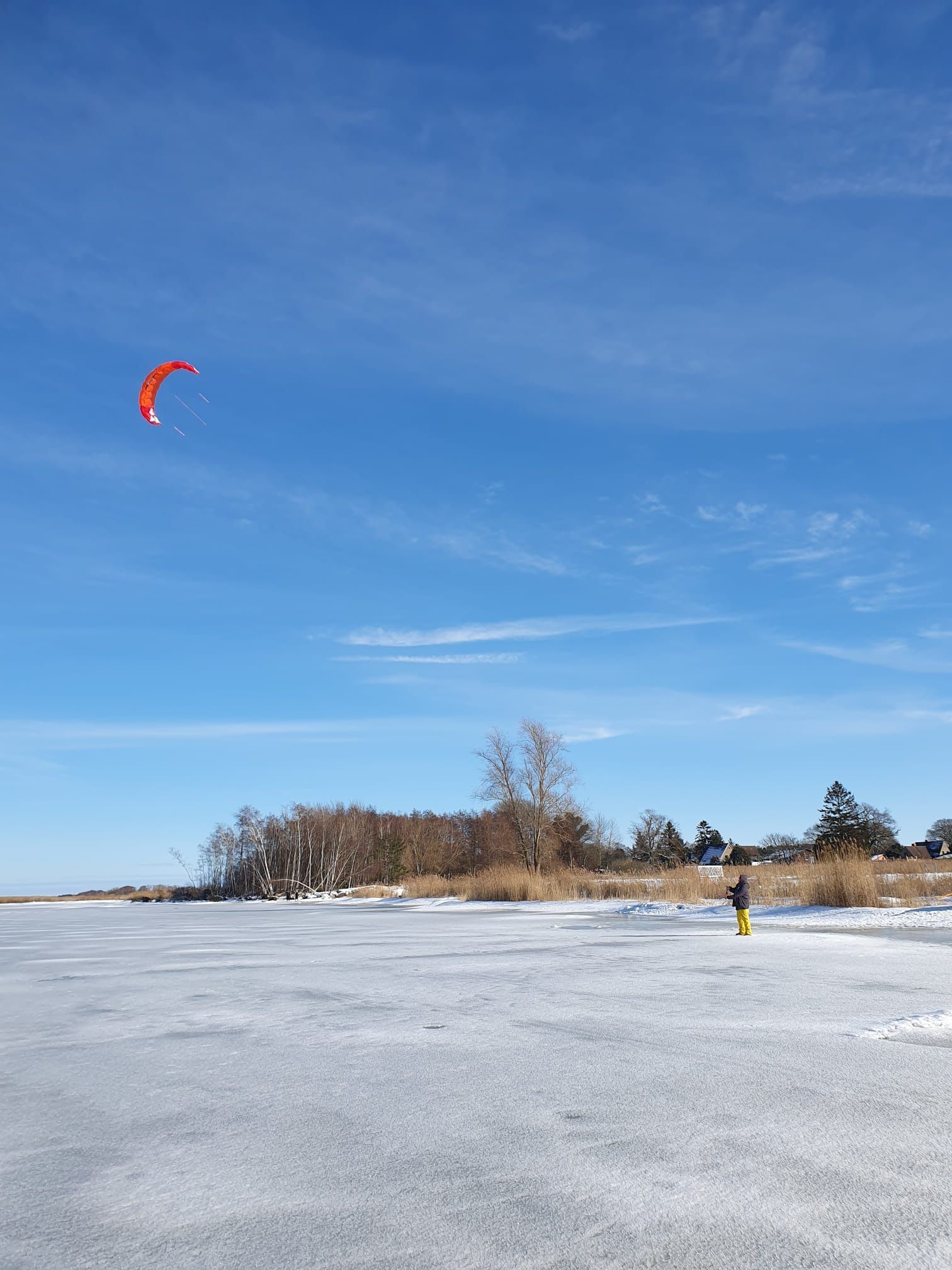 Un paysage hivernal, avec un ciel dégagé et une personne portant un pantalon jaune.