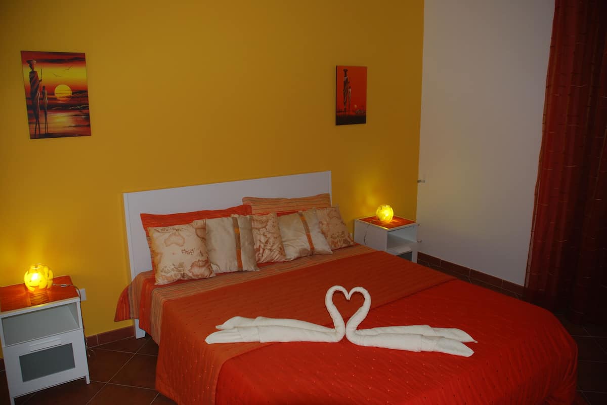 A hotel room with a large bed, two bedside tables, and a nightstand with a lamp.
