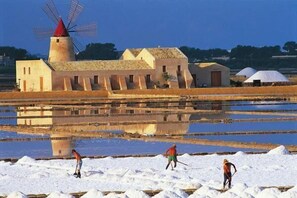 Een windmolen, een gebouw en werknemers in een zoutvlakte.